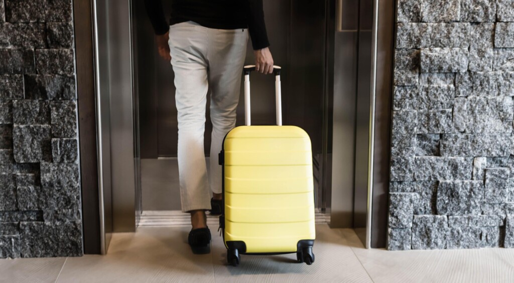 Mężczyzna wchodzący do windy z żółtą walizką