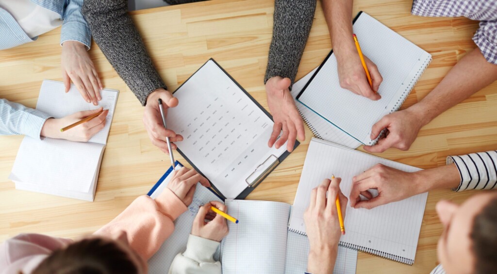 Ludzie siedzący dookoła stołu i rozmawiający nad dokumentami