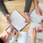 Ludzie siedzący dookoła stołu i rozmawiający nad dokumentami