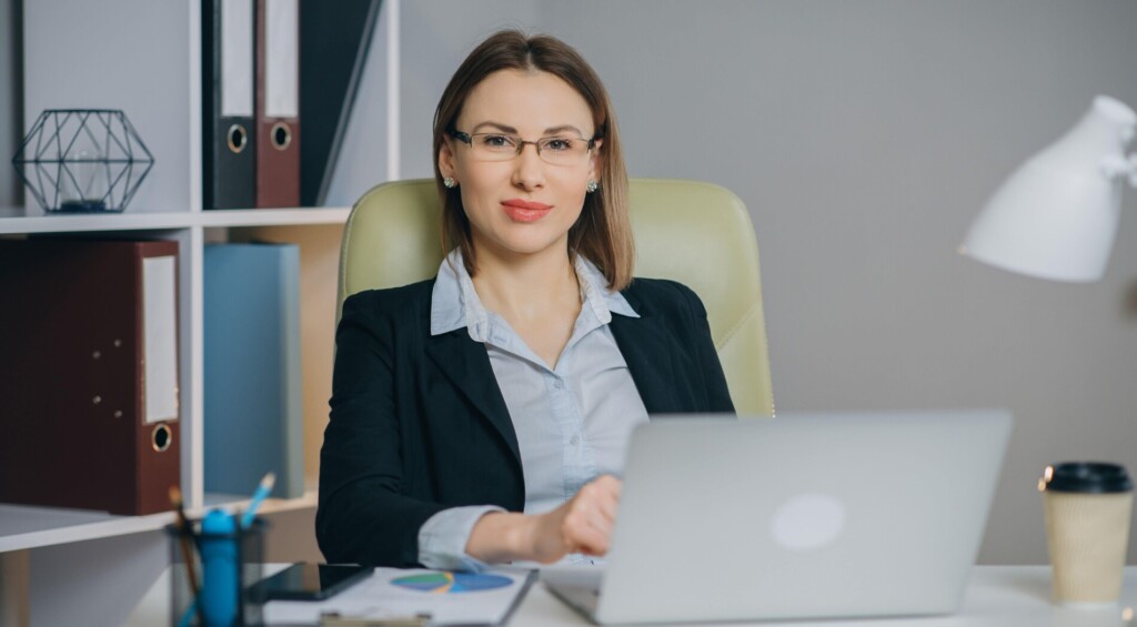 Kobieta w okularach pracująca z laptopem przy biurku