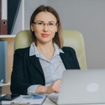 Kobieta w okularach pracująca z laptopem przy biurku